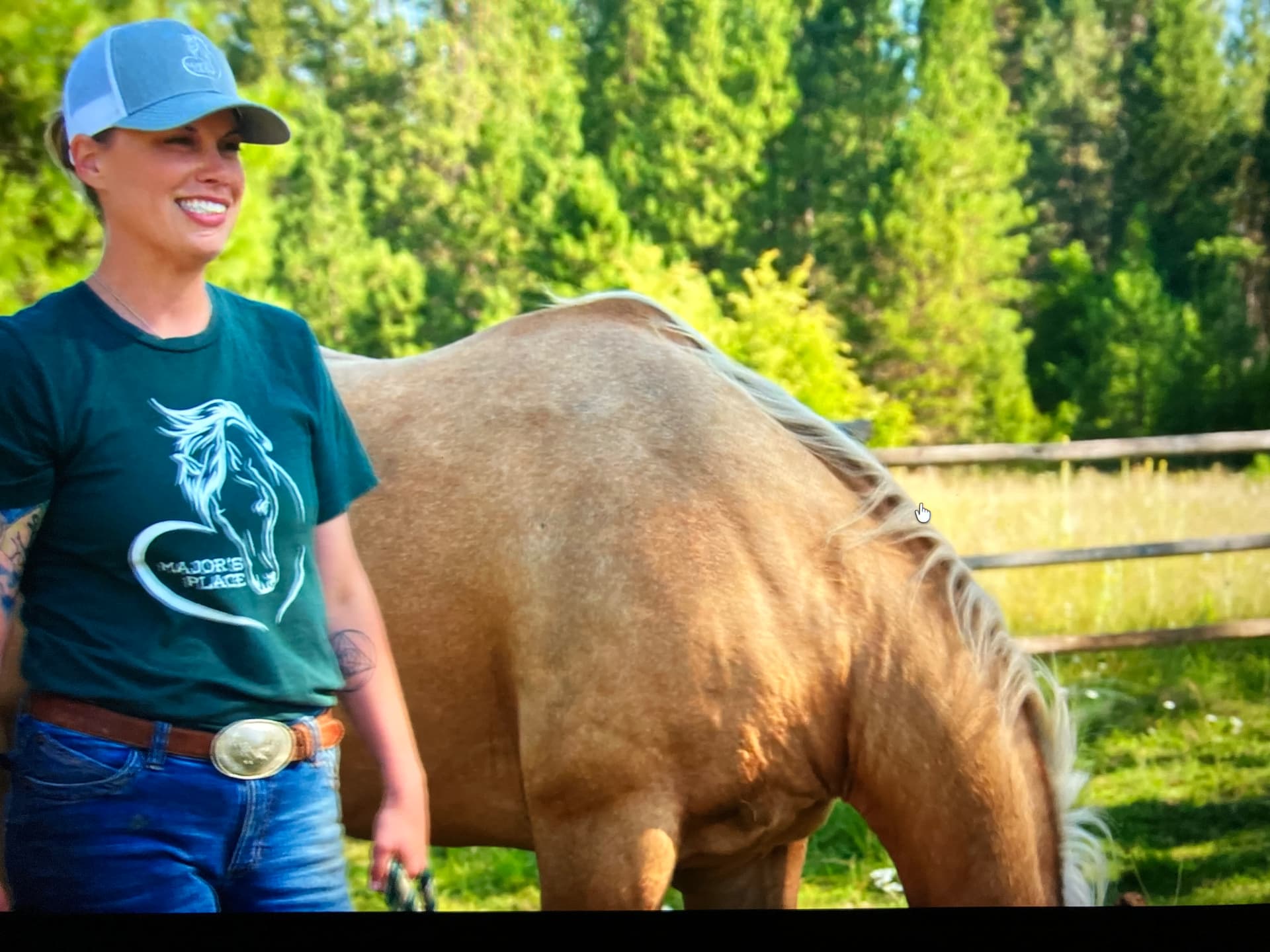 Anne-Marie smiling beside a grazing palomino horse