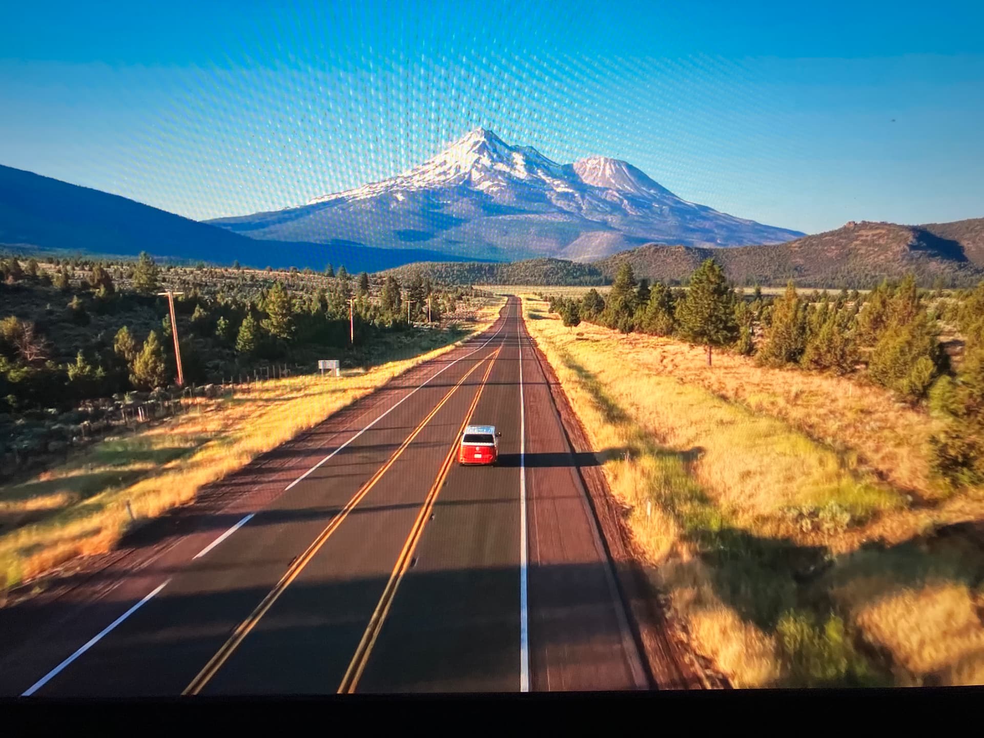 A red van on Highway 89 with Mount Shasta ahead