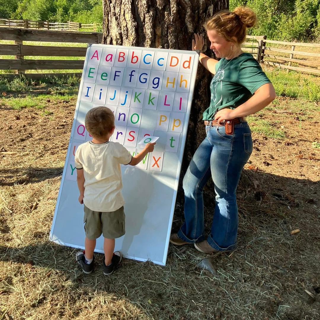 A student at an alphabet board with a facilitator and a horse